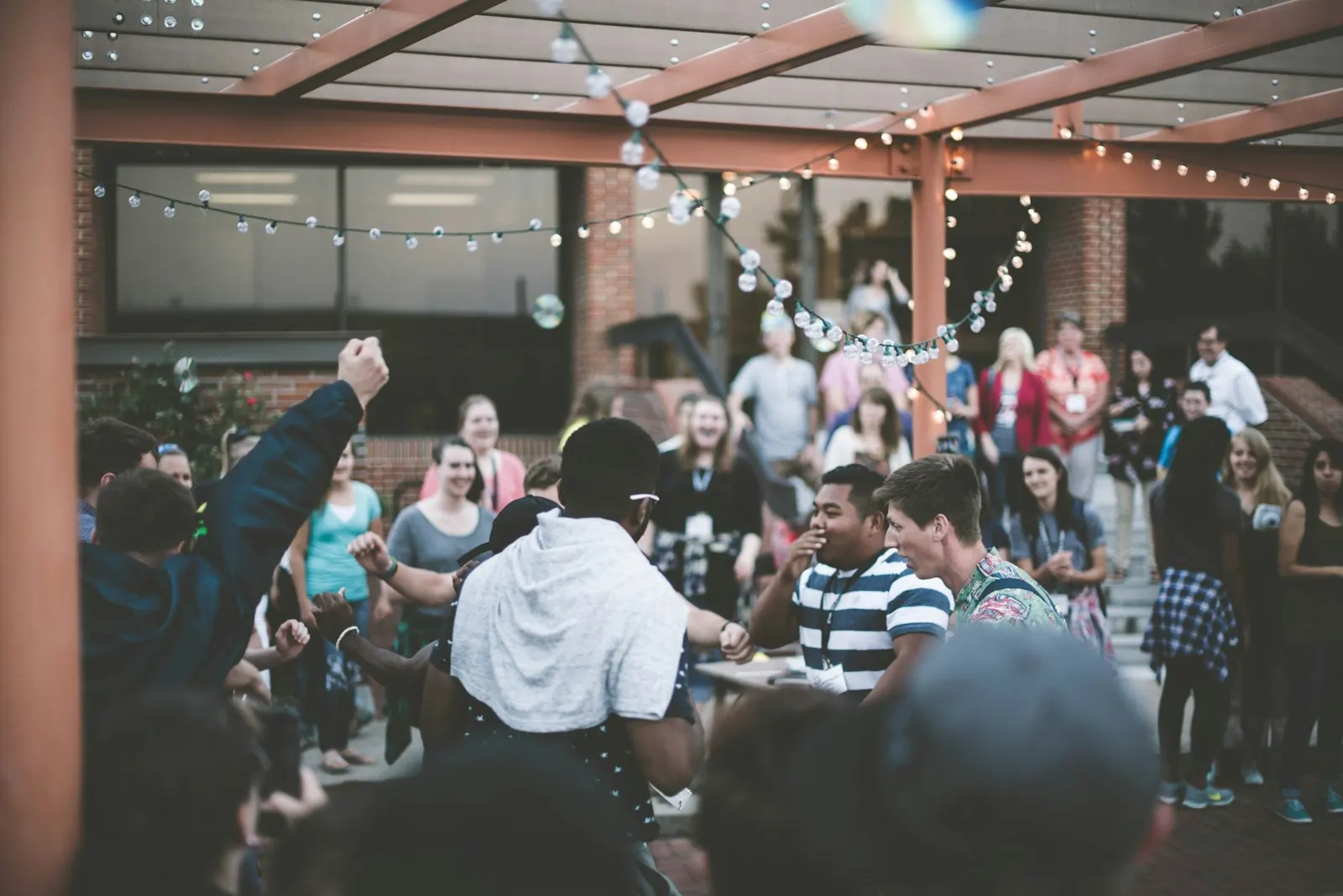 A community gathered outdoors beneath strings of lights